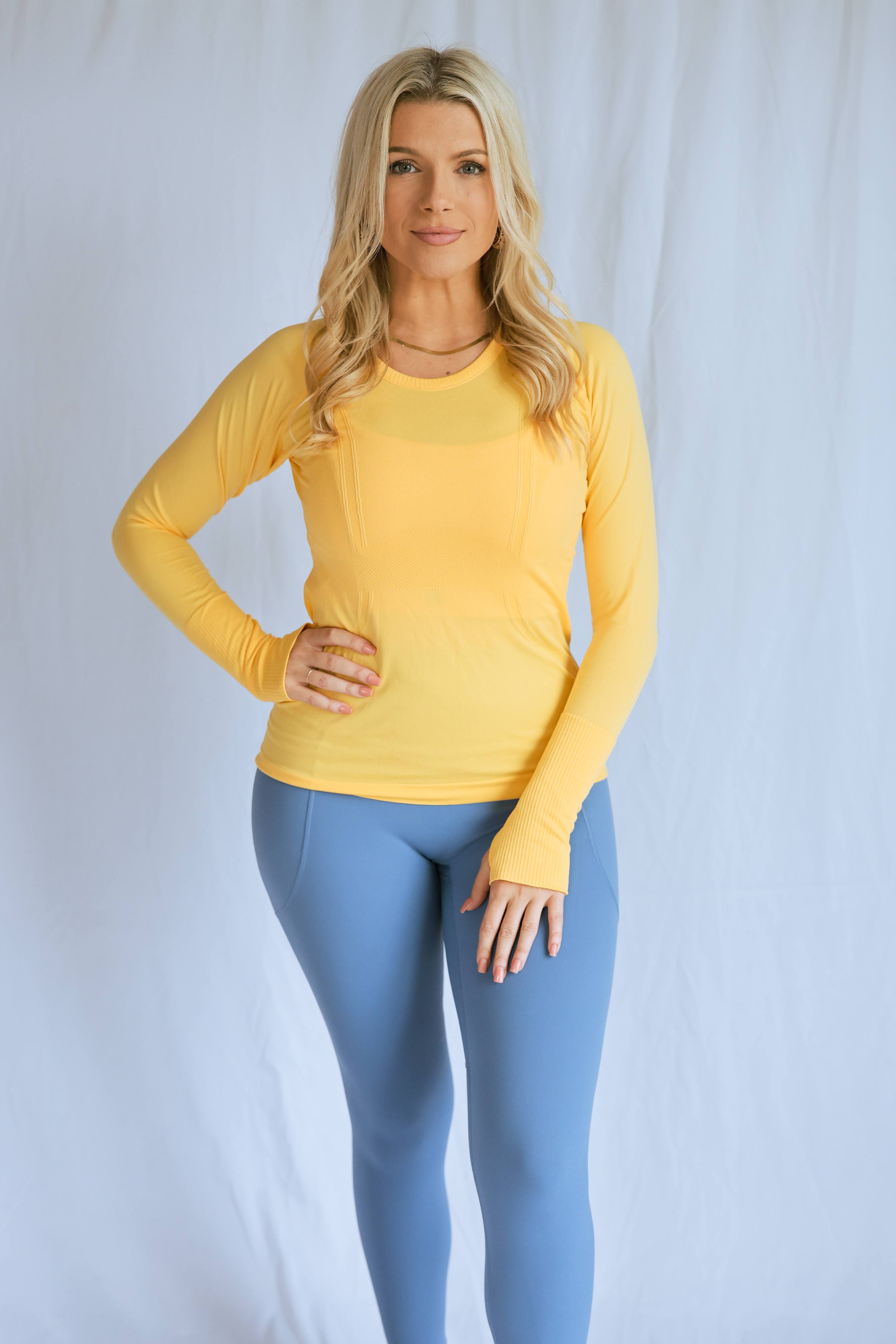 Model wearing the "breathe" long sleeve shirt from The Sweat Society. She is wearing the yellow color and looking at the camera. 