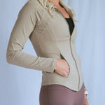 Model wearing the "smooth" fitted jacket from The Sweat Society. She is wearing the nude color and looking away from the camera. 