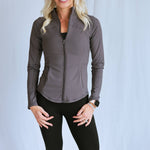 Model wearing "smooth" fitted jacket from the Sweat Society. She is wearing the grey color and smiling at the camera. 